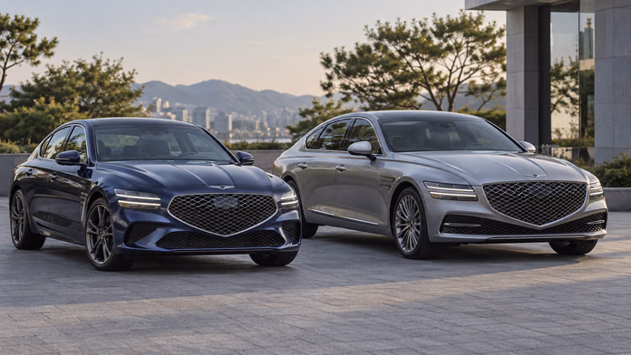 Синий Genesis G70 и серебристый G80 RG3 возле деревьев и здания — синтетическая редакционная иллюстрация