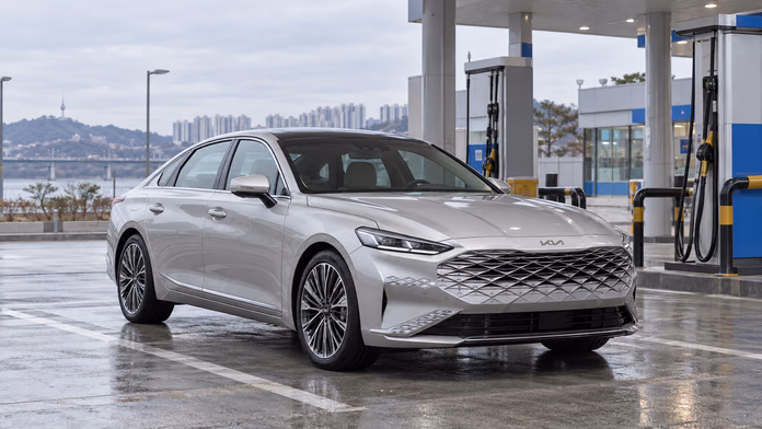 Серебристый Kia K8 у газозаправочной станции — синтетическая редакционная иллюстрация