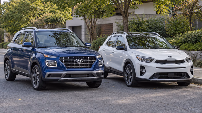 Синий Hyundai Venue и белый Kia Stonic возле здания и деревьев — синтетическая редакционная иллюстрация